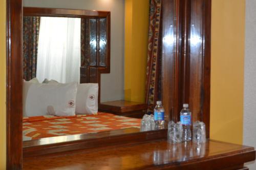 a mirror reflecting a bed with bottles of water on a table at Hotel Mina in Mexico City