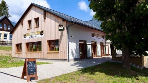 a building with a sign in front of it at Penzion a Restaurace u Sousedů in Strážný