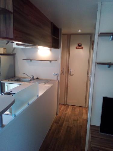 une cuisine avec évier et un couloir avec porte dans l'établissement Les Champs 42, à Vias