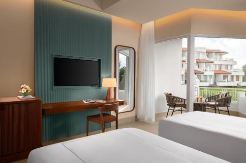 a bedroom with a bed and a desk with a television at Taj Bentota Resort & Spa in Bentota