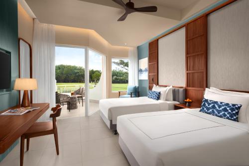 a hotel room with two beds and a balcony at Taj Bentota Resort & Spa in Bentota