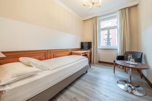 a bedroom with a bed and a table and a window at Hotel Neue Post I self check-in in Innsbruck