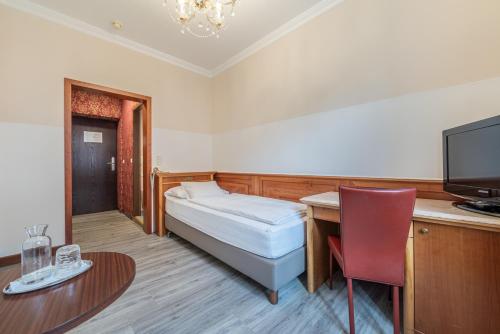 a small room with a bed and a desk with a television at Hotel Neue Post I self check-in in Innsbruck