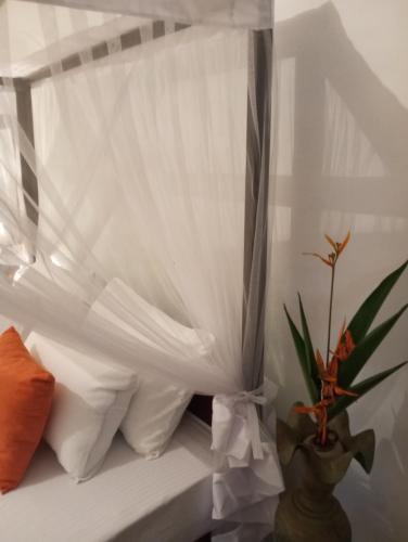 a bed with white curtains and a potted plant at Dishari Tangalle in Tangalle