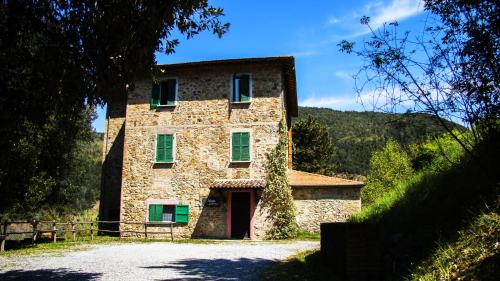 a large stone building with green windows on a road at La Casella Antico Feudo di Campagna in Ficulle