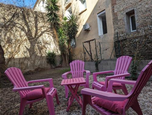 quatre chaises roses assises devant un bâtiment dans l'établissement Proche du centre ville, calme, climatisé, avec 2 salles d'eau, à Perpignan