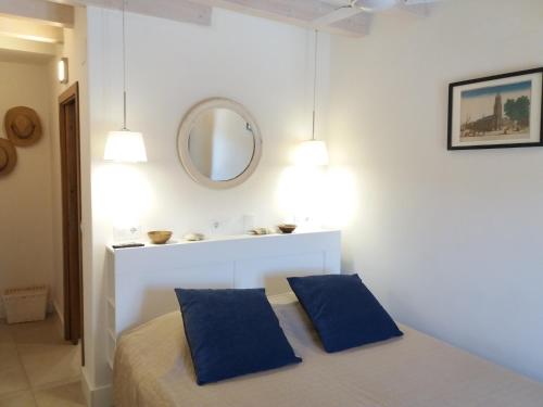 a white room with a bed with two blue pillows at Apartamentos Rurales Entre Fuentes in Cuacos de Yuste