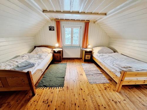 two beds in a room with wooden floors and a window at Haus Völlegg in Völlegg