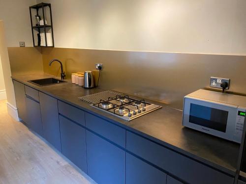 a kitchen with a stove and a microwave at Collingwood House Tynemouth in Tynemouth
