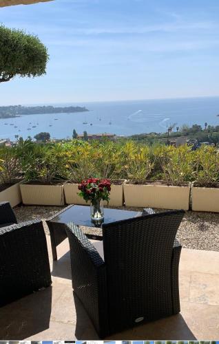 a table with chairs and a vase of flowers on it at Villa Grand Baie in Agay - Saint Raphael