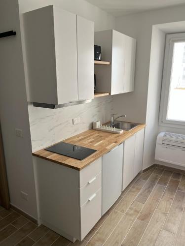 une cuisine avec des armoires blanches et un évier dans l'établissement Renovated Seaside Studio in the Heart of Menton, à Menton