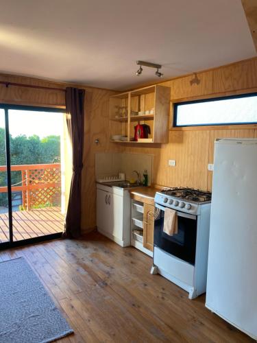 a kitchen with a stove and a white refrigerator at Cabañas Cerro Tacna in Maitencillo