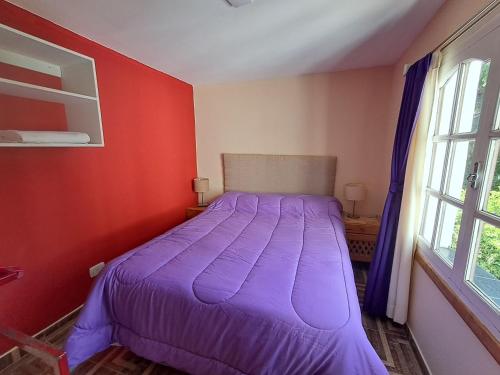 a bedroom with a purple bed in a red wall at La Esquina in Esquel