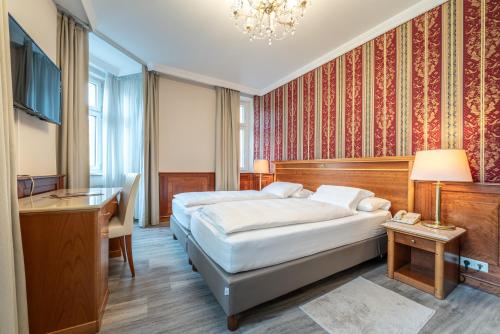a hotel room with two beds and a desk at Hotel Neue Post I self check-in in Innsbruck