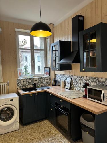 La cuisine est équipée de placards noirs, d'un évier et d'un four micro-ondes. dans l'établissement Appartement cosy sur Nancy, à Nancy