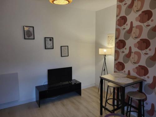un salon avec une table et une télévision dans l'établissement Deguise 8, à Valenciennes