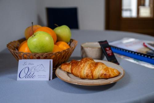 a table with a plate of food and a bowl of fruit at Chambres d'Hôtes La Petite Odile in Boersch