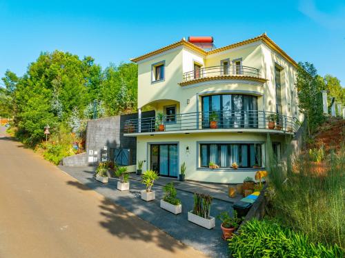 a house with potted plants on the side of a road at Vienna apartment Alpine escape villa in Achada de Gaula