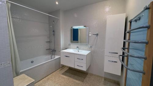 une salle de bain avec un lavabo, une baignoire et un miroir dans l'établissement Amazing view in Montmartre, 2 min from Sacre-Coeur, à Paris