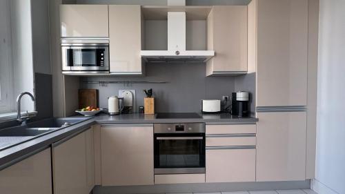 une cuisine avec des armoires blanches et des appareils en acier inoxydable dans l'établissement Amazing view in Montmartre, 2 min from Sacre-Coeur, à Paris