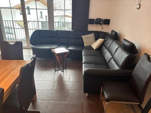 a living room with a black leather couch and a table at Alpinchalet Eder - Steiner in Saalbach-Hinterglemm