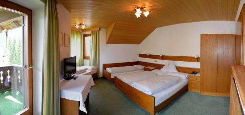 a bedroom with two beds and a tv in it at Garni Sayonara in San Vigilio Di Marebbe