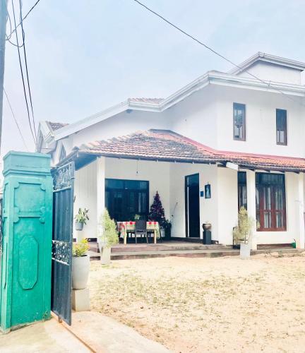 a white house with a green gate in front of it at Sebastian Family Villa in Negombo