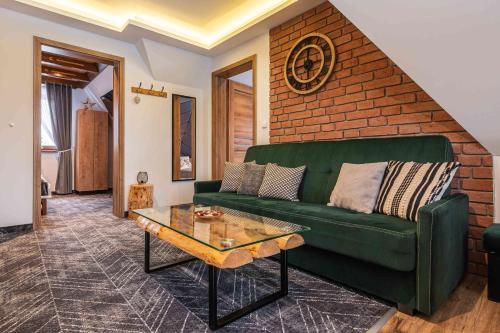 a living room with a green couch and a brick wall at Goralove Pole in Brzegi