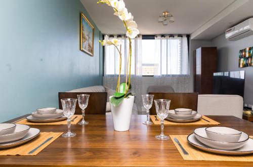 a table with plates and glasses and a vase with flowers at Stylish and Modern Oasis in Windhoek