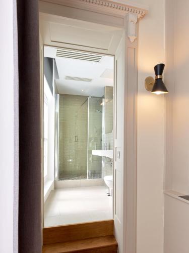 a bathroom with a glass door leading into a bathroom with a toilet at Hotel De Guise Nancy Vieille Ville in Nancy