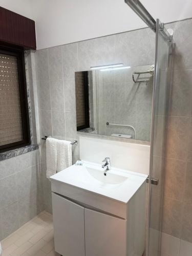 a bathroom with a white sink and a shower at Residencial Pôr do Sol in Couço