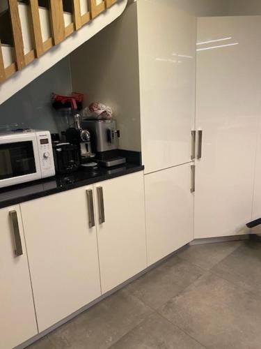 une cuisine avec des armoires blanches et un micro-ondes dans l'établissement Séjour proche Paris & Disney, à Lésigny