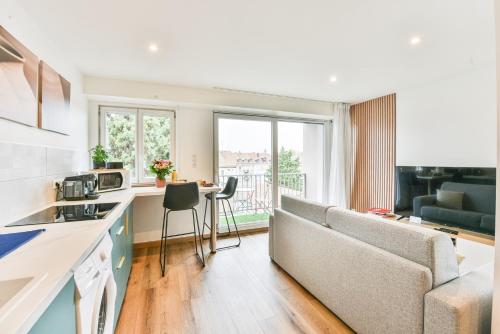 une cuisine et un salon avec un canapé et une table dans l'établissement Le Repaire Du Grizzly, à Mulhouse