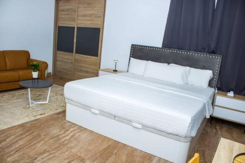 a bedroom with a large white bed and a couch at Hotel Mandarin in Accra