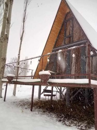 a cabin in the snow with a bench in front at Zovaber hangsti goti in Sevan