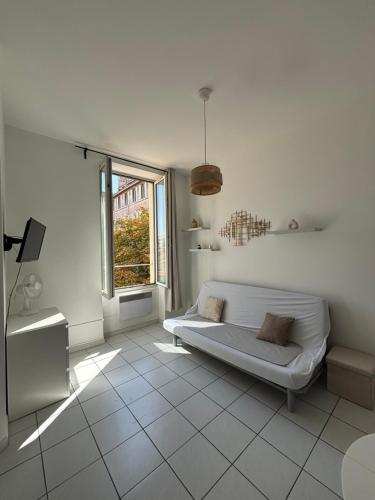 - un salon blanc avec un canapé et une fenêtre dans l'établissement Le 23B, à Marseille