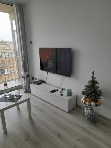 een woonkamer met een televisie aan een witte muur bij Studio Seasant in Nieuwpoort