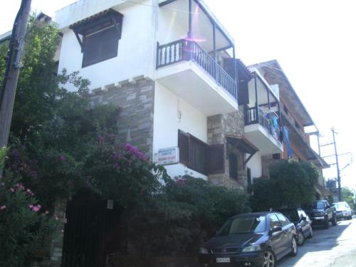 a building with a balcony and cars parked on the street at Papatzikos Traditional Guesthouse in Neos Marmaras