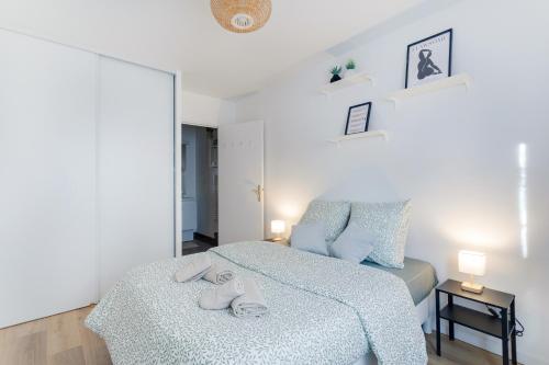 a white bedroom with a bed and a chair at Le Cocon Stade de France - Aux Portes de Paris - Parking Inclus in Saint-Denis