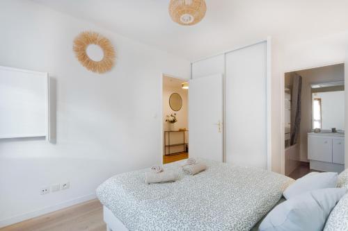 une chambre blanche avec un lit et un miroir dans l'établissement Le Cocon Stade de France - Aux Portes de Paris - Parking Inclus, à Saint-Denis