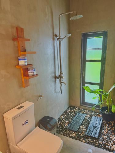 a bathroom with a shower and a toilet and a window at The Jini House in Ahangama