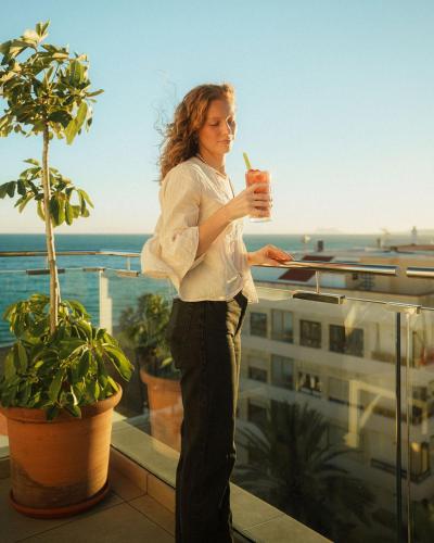 a woman standing on a balcony holding a drink at Hotel Estepona Plaza in Estepona