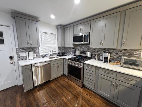 a kitchen with stainless steel appliances and wooden floors at Brand New 4BR House 20Min Downtown Boston in Boston