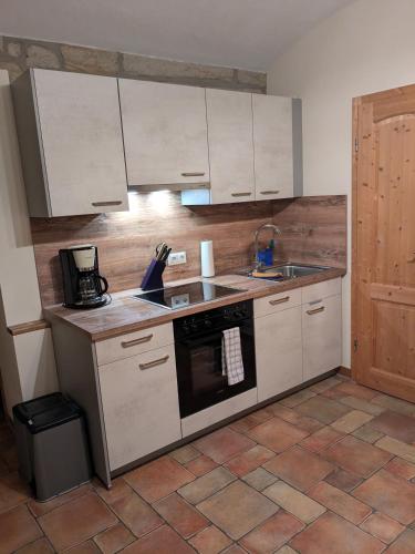 a kitchen with white cabinets and a sink and a stove at Ferienwohnung "WILLI" in Hohnstein