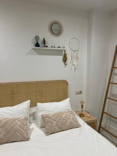 a bedroom with a bed with white sheets and a mirror at Ático playa Palmás in Moaña
