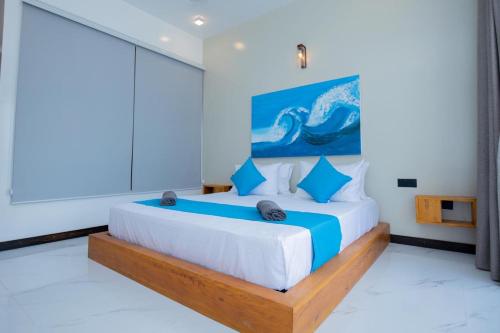 a bedroom with a large bed with blue pillows at Liya Beach Kathaluwa - Ahangama in Ahangama
