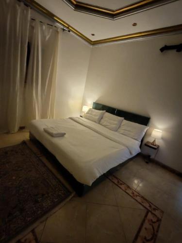 a bedroom with a large bed with white sheets and pillows at الينبوع الأخضر in Al Madinah