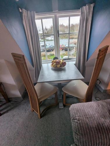 a table with chairs and a bowl of fruit on it at Willow Cottage in Horning