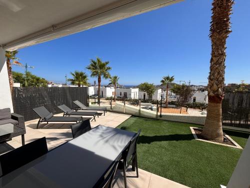 eine Terrasse mit Tischen, Stühlen und einer Palme in der Unterkunft Martormar in Finestrat