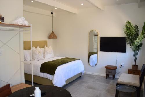 a bedroom with a bed and a tv on the wall at House on Pringle in Cape Town